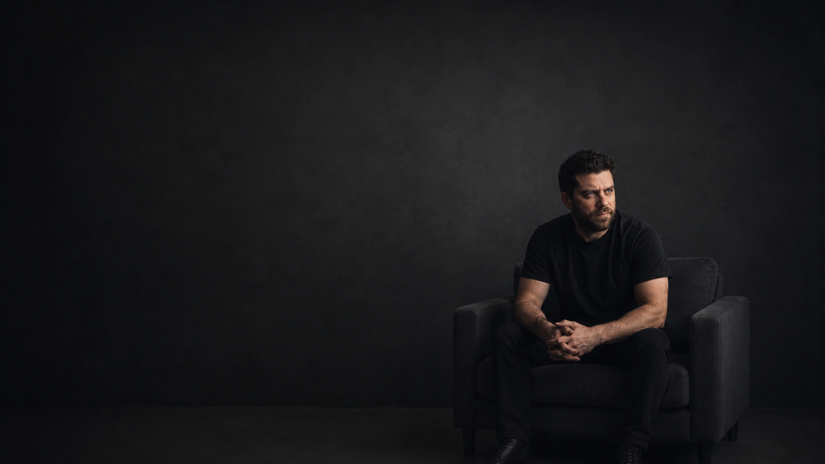 Portrait of Jaymie Jones seated in a dark studio